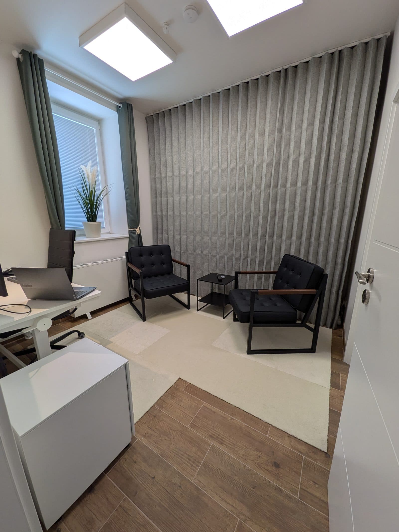 Raum 2 mit Schreibtisch, Sitzecke und grauem Akustikvorhang
